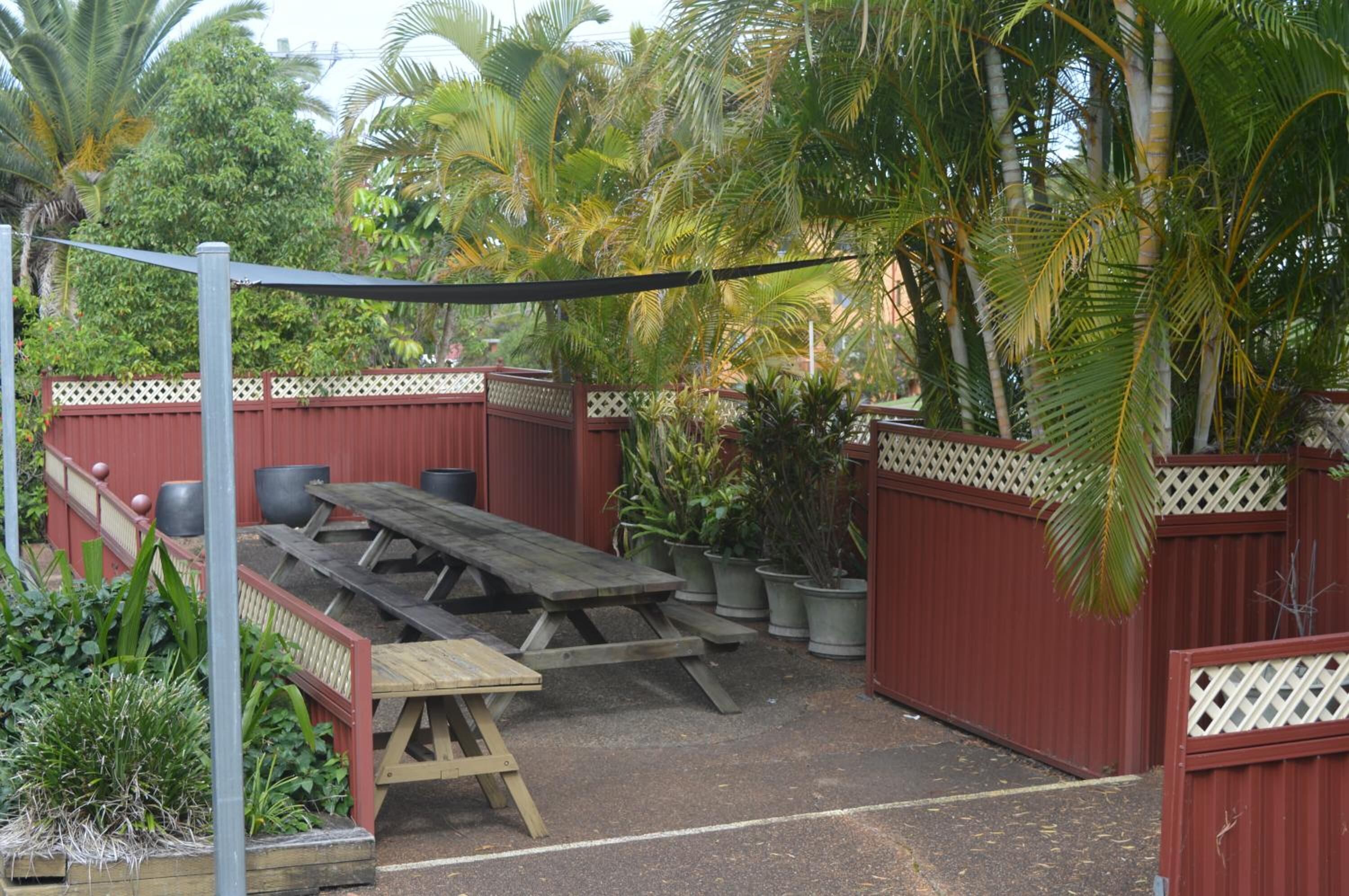A covered outdoor seating area with picnic tables and potted plants.