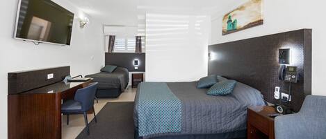 A hotel room with a bed, a desk, a chair, a TV, and a painting on the wall.