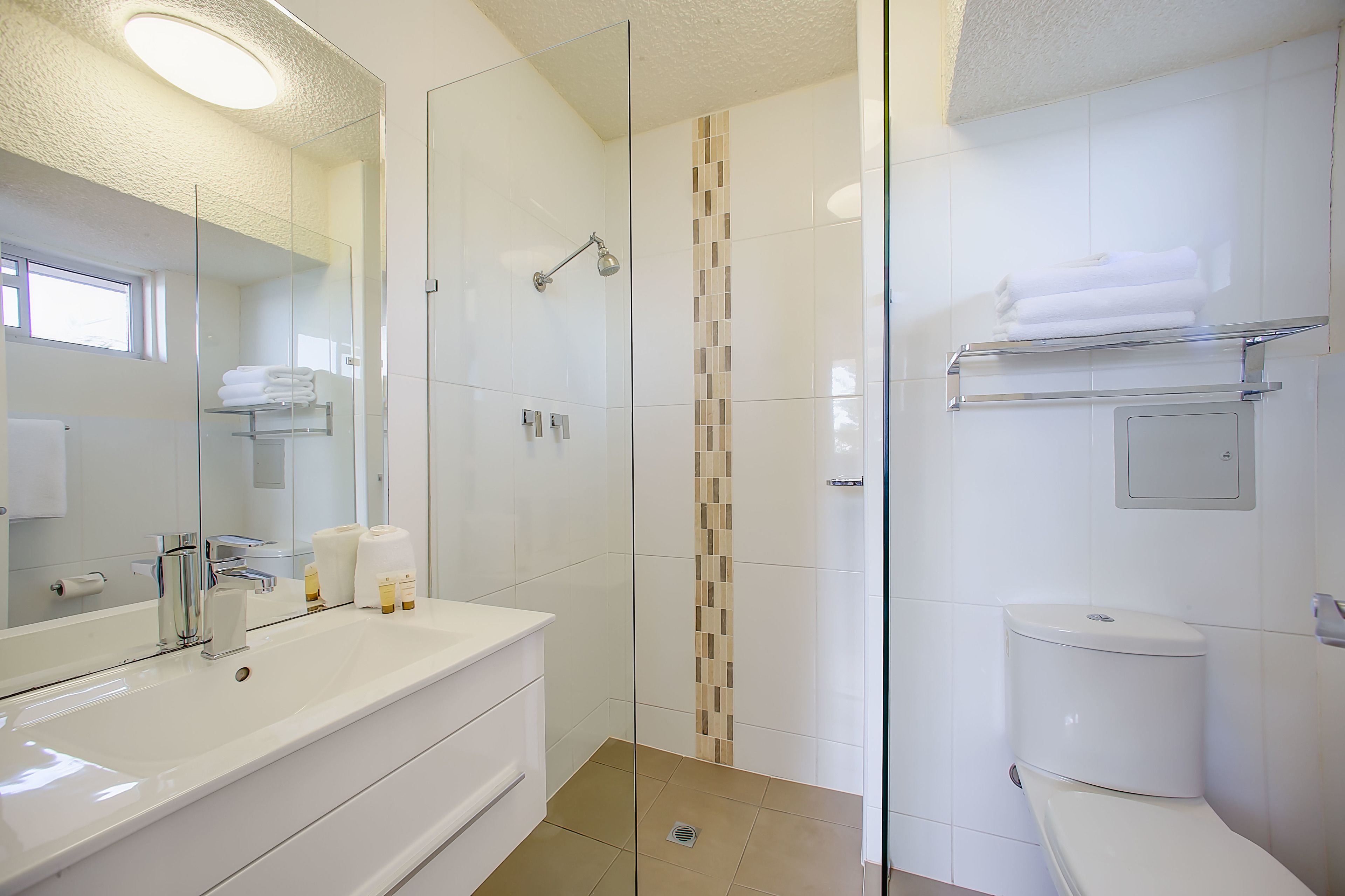 Une salle de bain moderne avec une douche à parois de verre, un lavabo blanc et des toilettes.