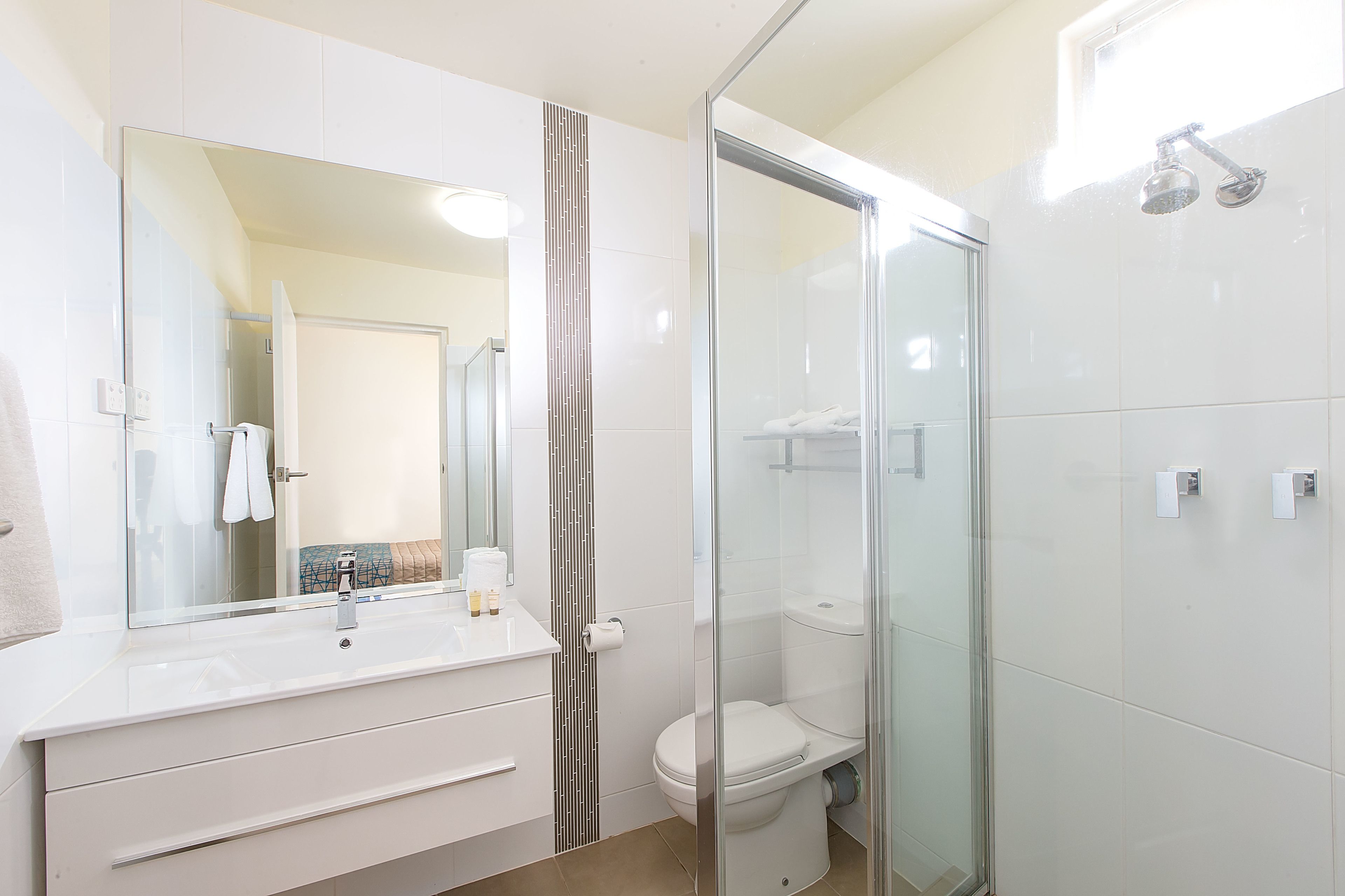A modern bathroom with a glass shower enclosure, a white sink, and a toilet.