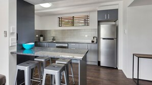 A modern kitchen with grey cabinets, stainless steel appliances, and a grey countertop. - El Motor Inn (Port Macquarie)