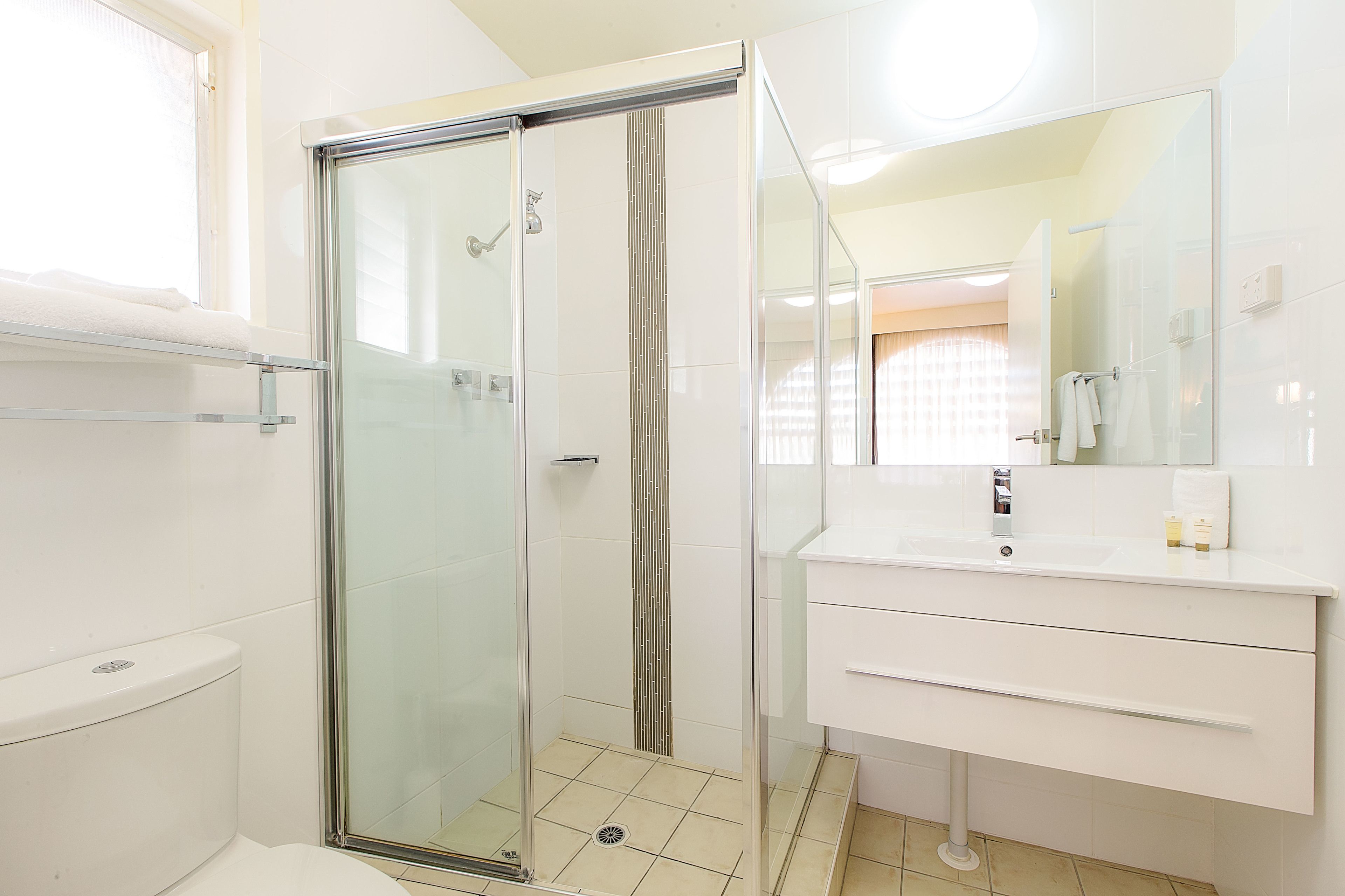 Une salle de bain moderne avec une douche à parois de verre, un lavabo blanc et un grand miroir.