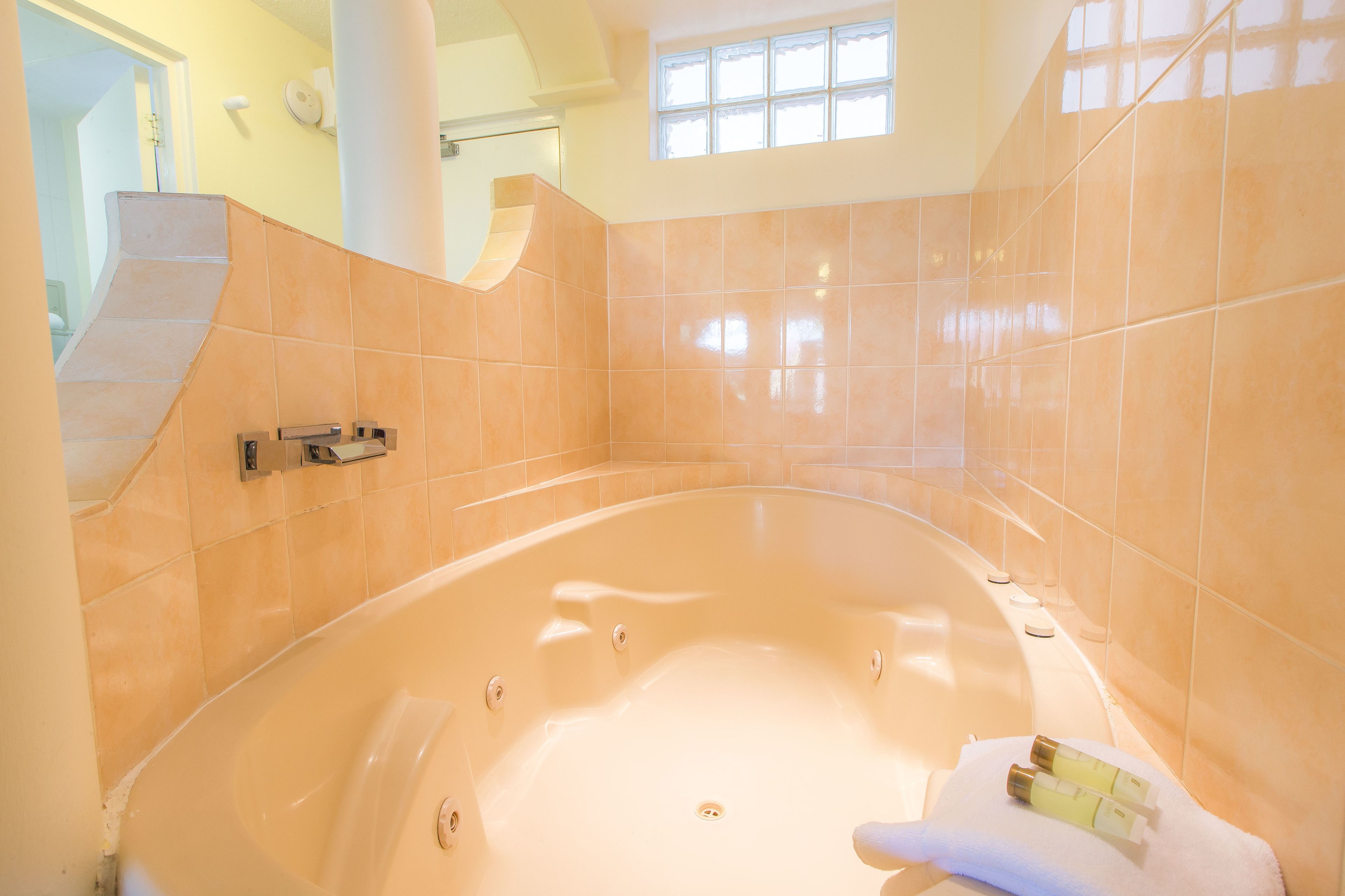A modern bathroom with a large bathtub, tiled walls, and a window providing natural light.