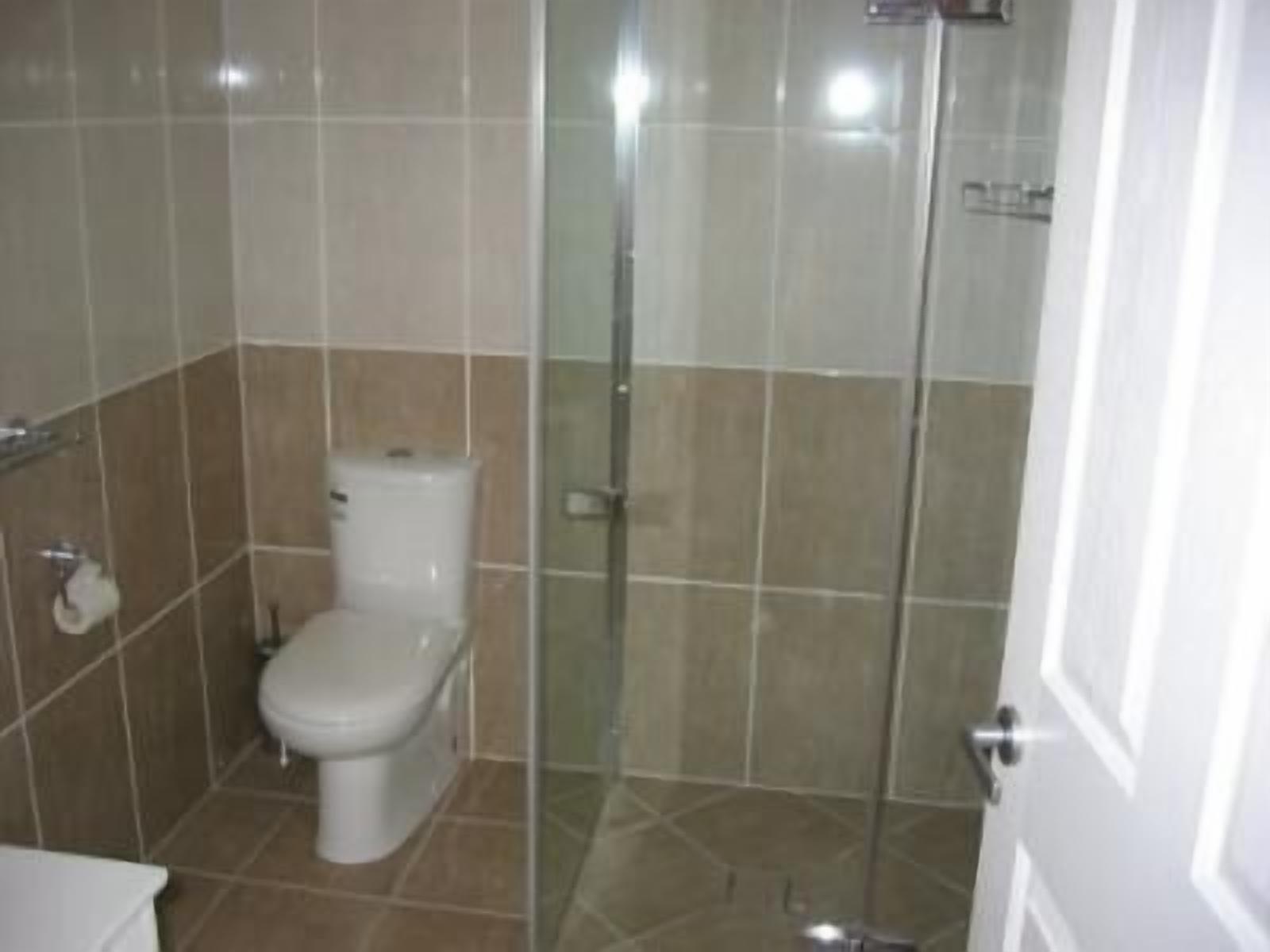 Een badkamer met een toilet, een douchecabine en een toiletrolhouder aan de muur.