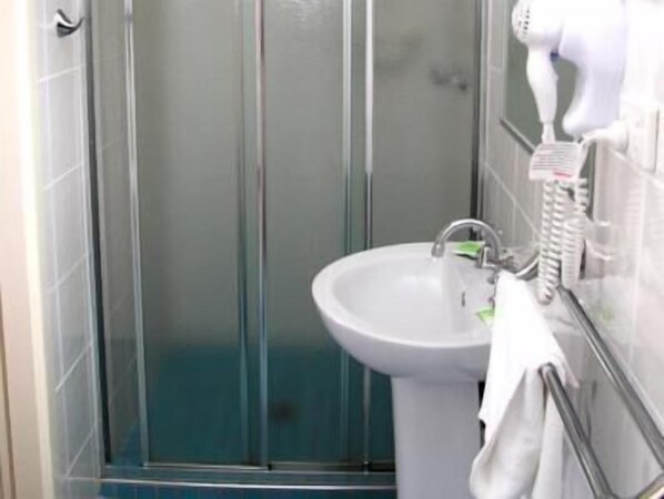 A bathroom with a glass shower enclosure, a white sink, and a towel rack.