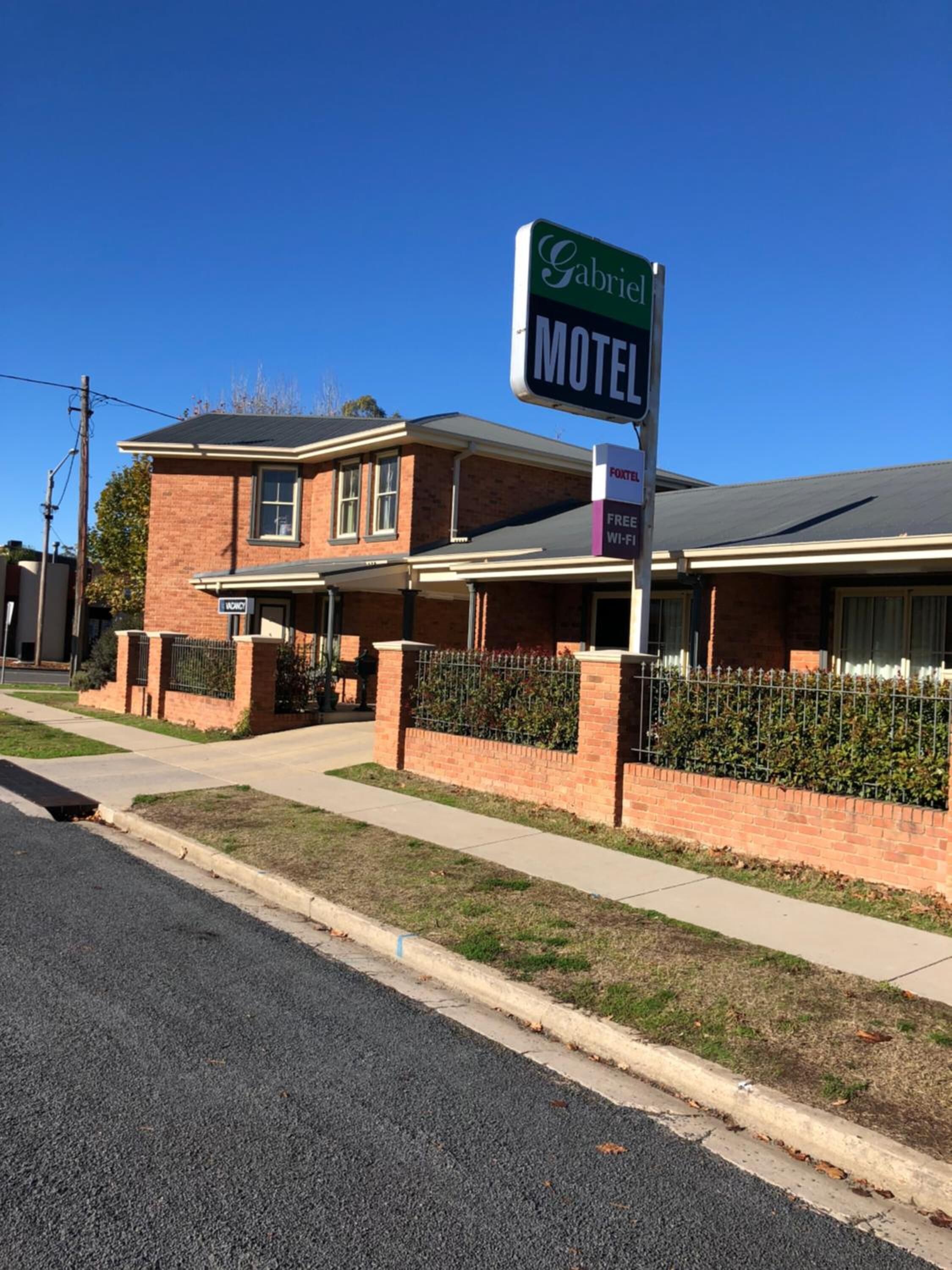 A motel named Gabriel with a signboard, a brick building, and a fenced parking area.