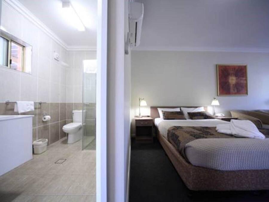Camera d'albergo con un letto, comodini, un bagno con il water e una doccia.