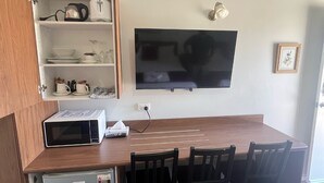 A compact living space with a kitchenette, a flat-screen TV mounted on the wall, and a dining area with chairs. - Gabriel Motor Inn (Gundagai)