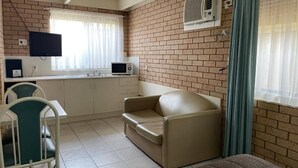 A compact room with a kitchenette, a sofa, a television, and a window with curtains. - Citrus Motel (Griffith)