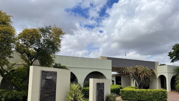 A modern building with a flat roof, multiple arches, and a stone accent wall. - Citrus Motel (Griffith)