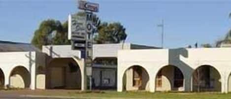 Un motel con varias ventanas arqueadas y un letrero.