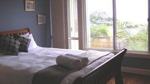 Une chambre à coucher avec un lit, une chaise, une fenêtre et une vue sur l’extérieur.