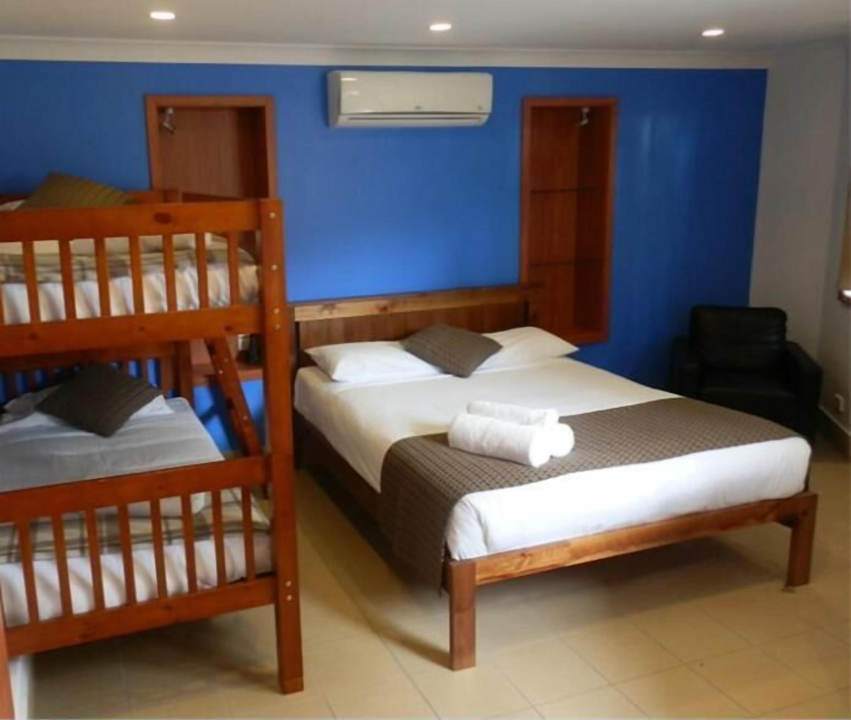 A room with a bunk bed, a single bed, and a chair.