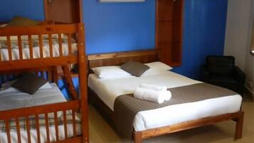 A room with a bunk bed, a single bed, and a chair.