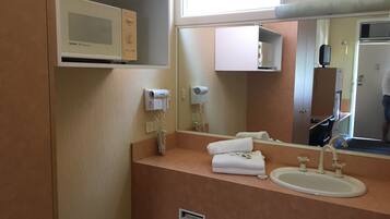 Un baño de hotel con lavamanos, dispensador de toallas y espejo.