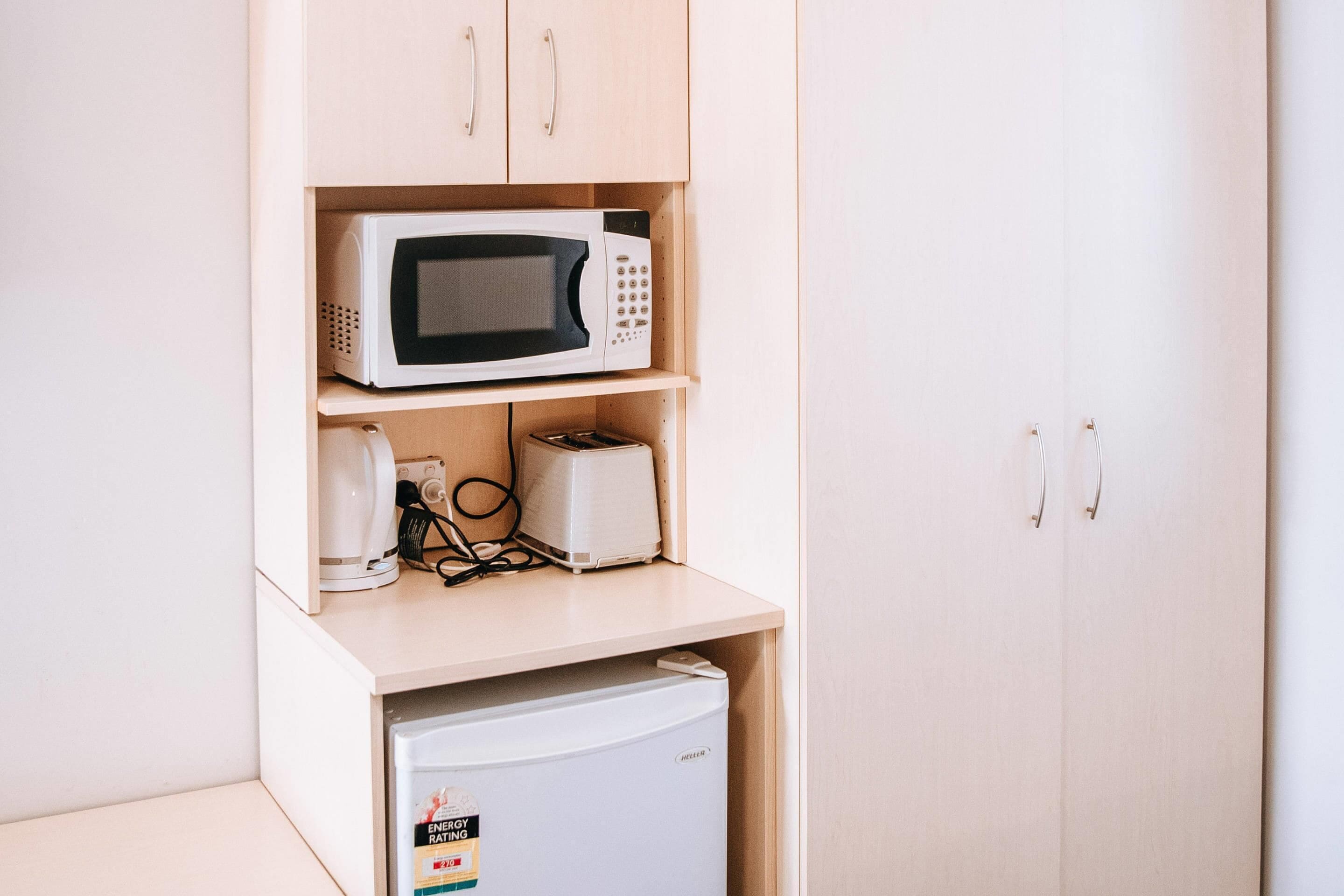 A kitchenette with a microwave, toaster, and refrigerator.