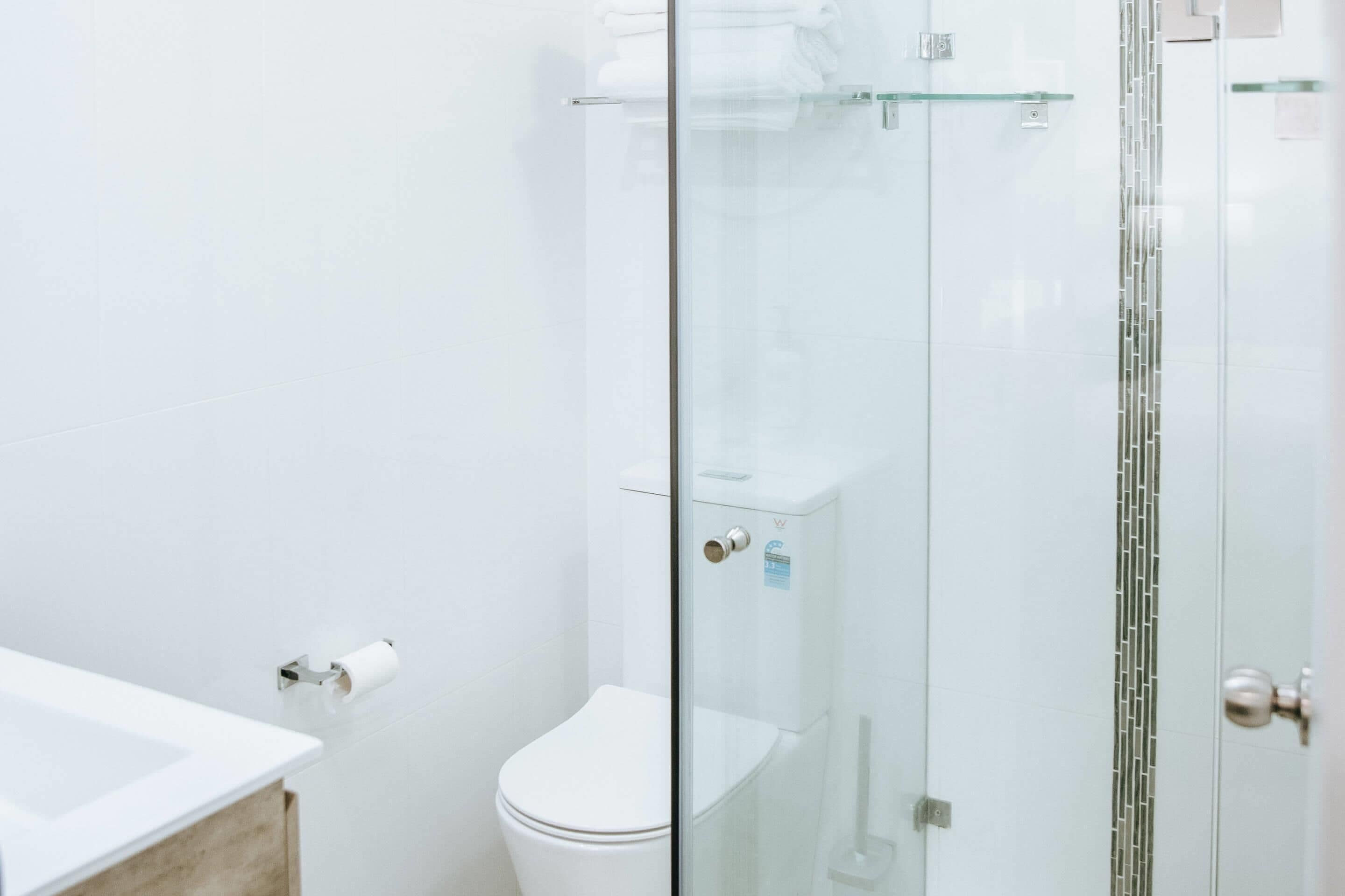 A modern bathroom with a glass shower enclosure, a white toilet, and a wooden vanity.