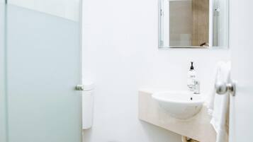 Un baño moderno con un lavabo blanco, un espejo y un inodoro.
