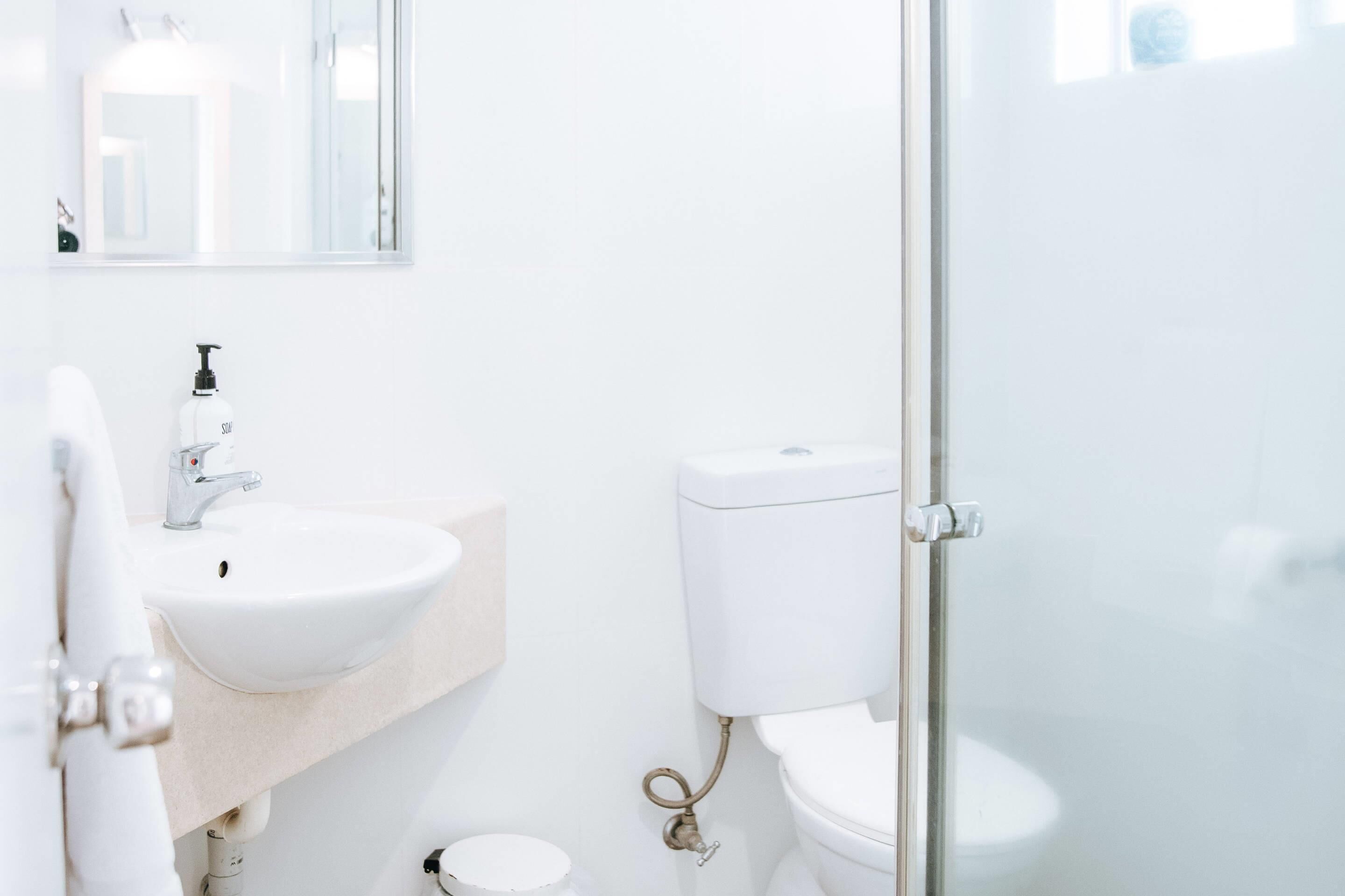 Un baño moderno con un lavamanos blanco, un inodoro y una cabina de ducha de vidrio.