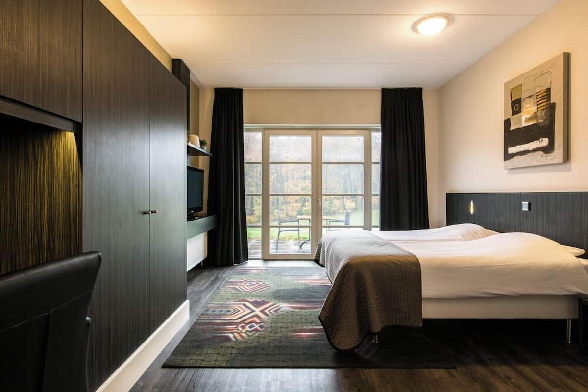Een hotelkamer met een bed, een televisie, een kledingkast en uitzicht op het omliggende landschap.