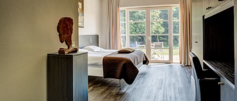 Un dormitorio con una cama, un ventanal grande y un televisor.