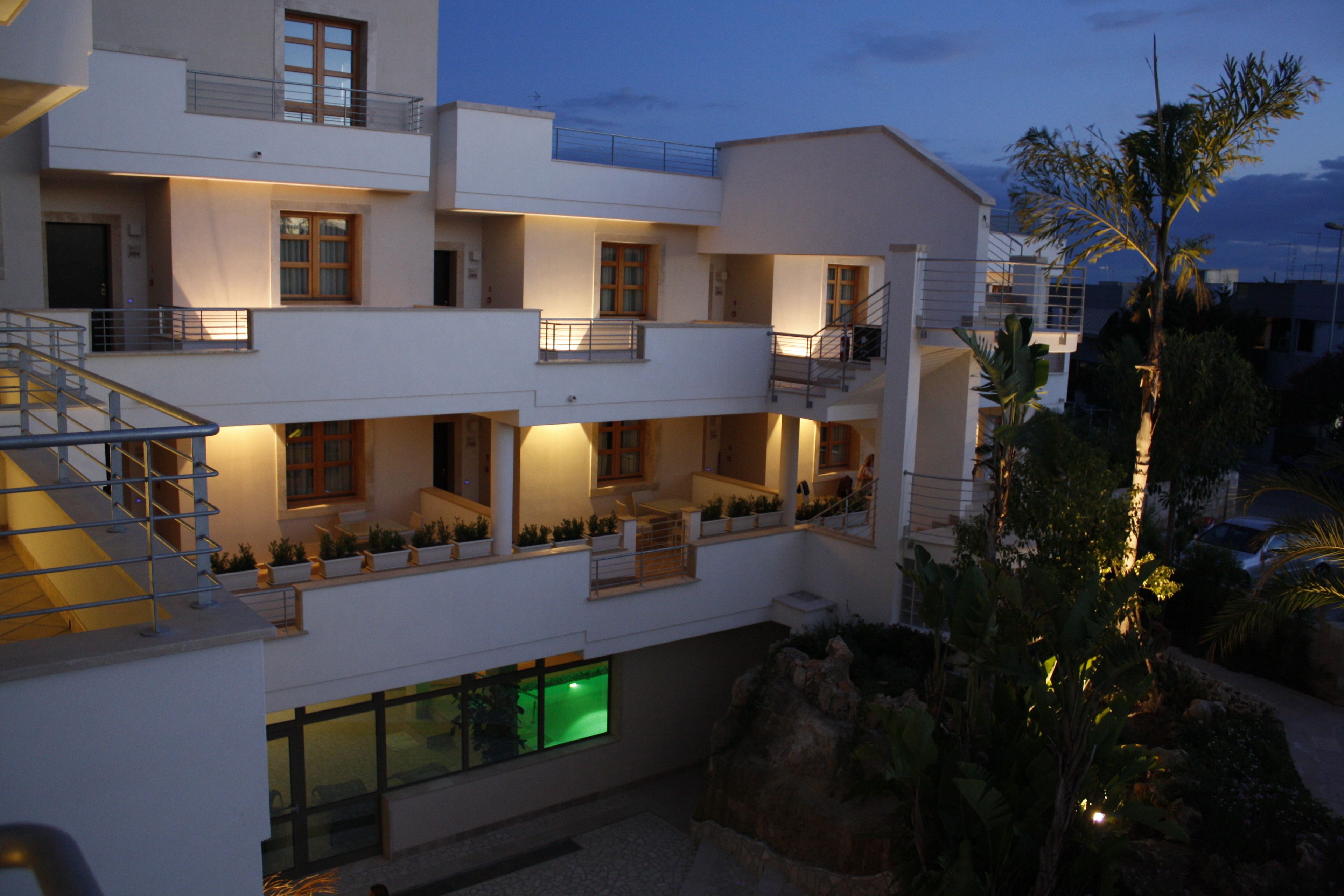 A multi-story hotel with balconies, a pool, and a landscaped garden.