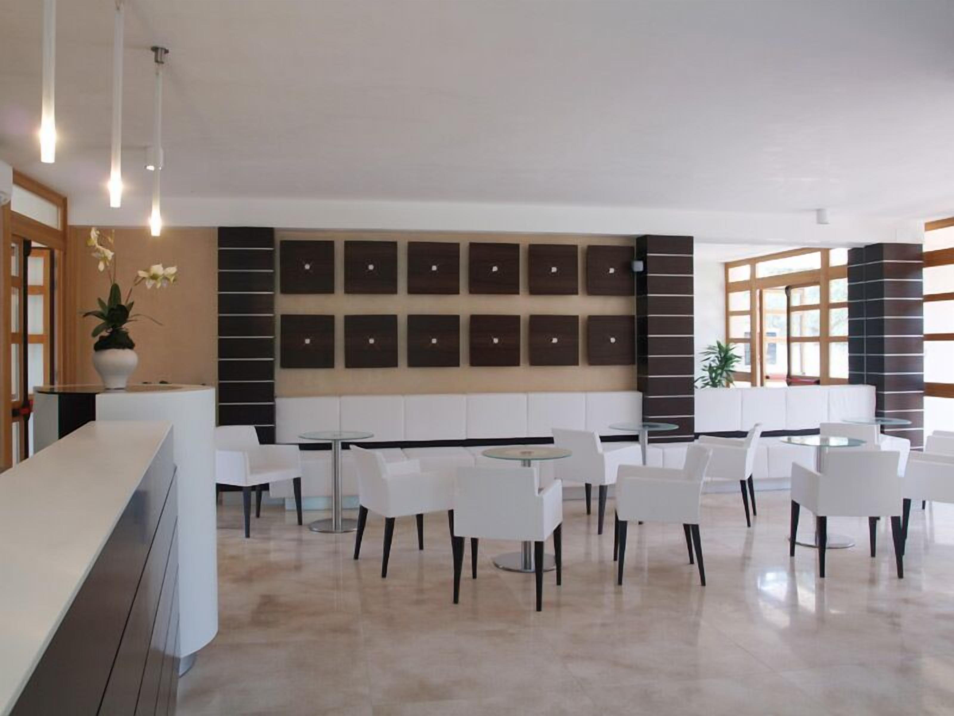 Een moderne hotellobby met een receptiebalie, een zithoek en decoratieve wandpanelen.