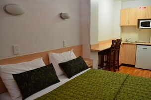 Una habitación de hotel con cama, escritorio y kitchenette.