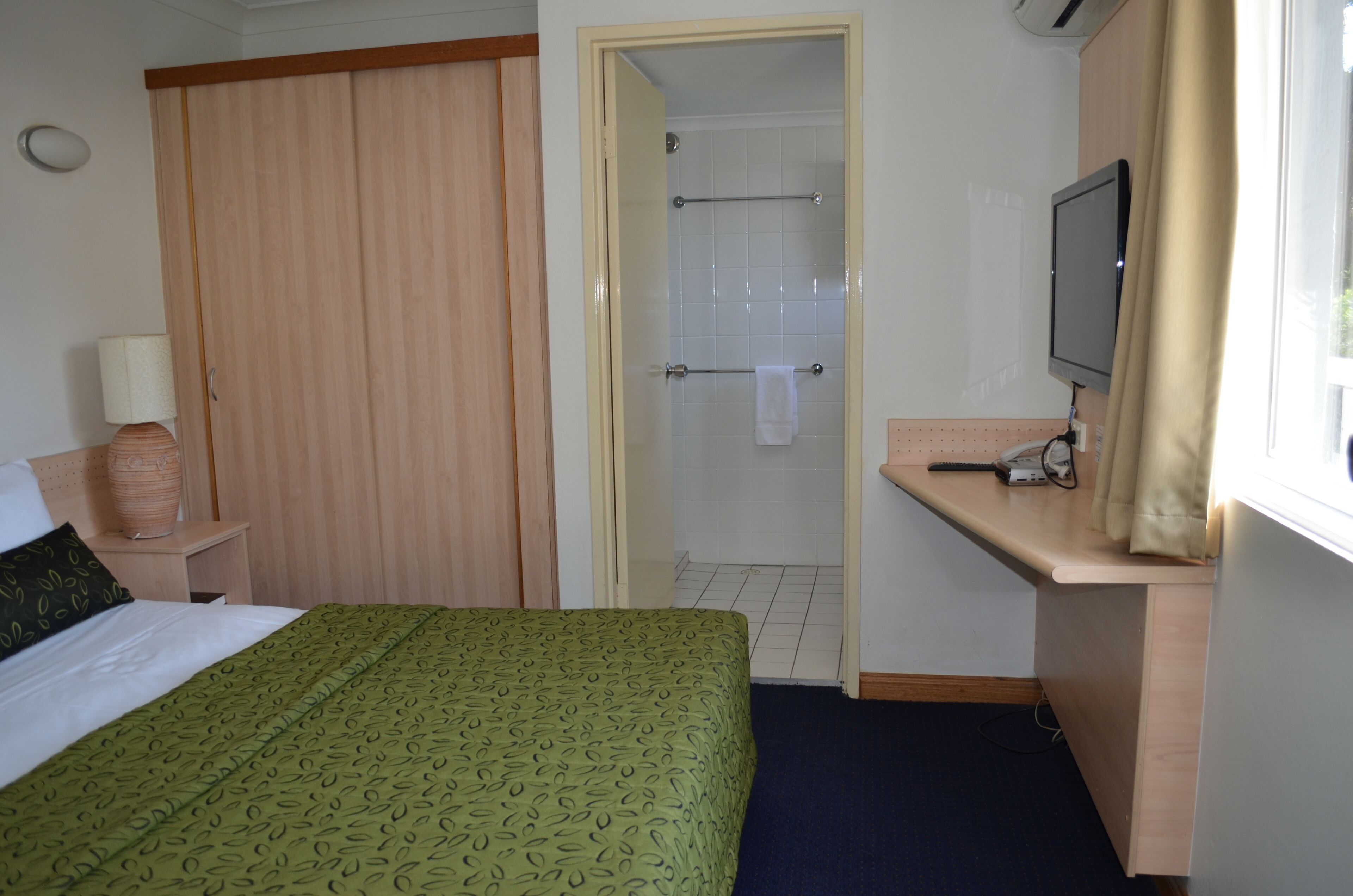 Hotellihuone, jossa on sänky, työpöytä, televisio ja suihkutila.