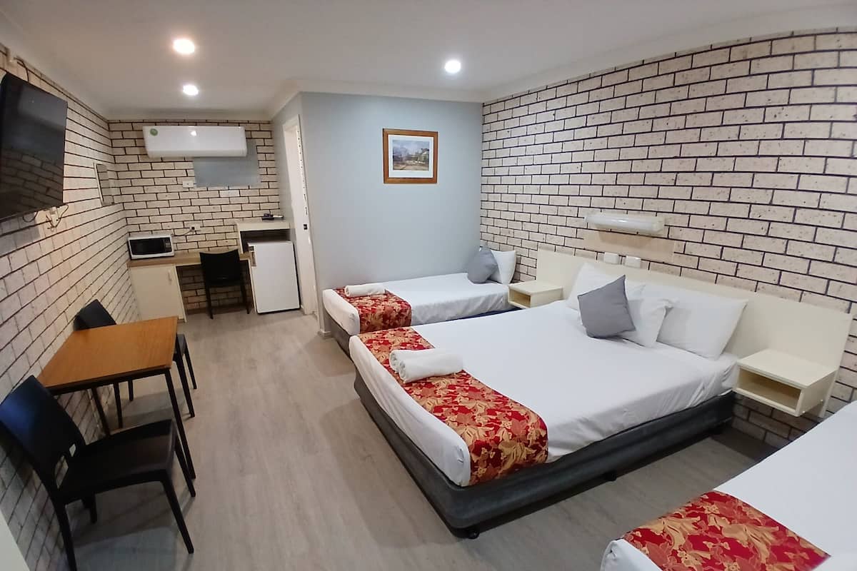 Habitación de hotel con dos camas, un escritorio, microondas y una pequeña kitchenette.
