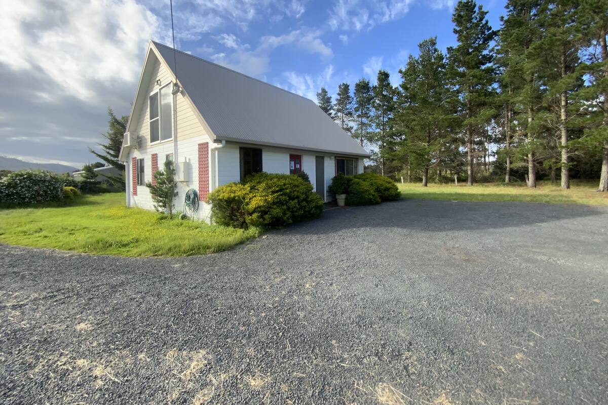 A two-story house with a sloped roof, a gravel driveway, and a well-maintained lawn.