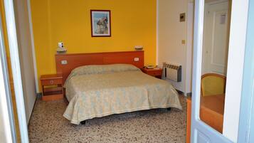 Une chambre à coucher avec un lit, des tables de chevet, une commode, un radiateur et un tableau au mur.