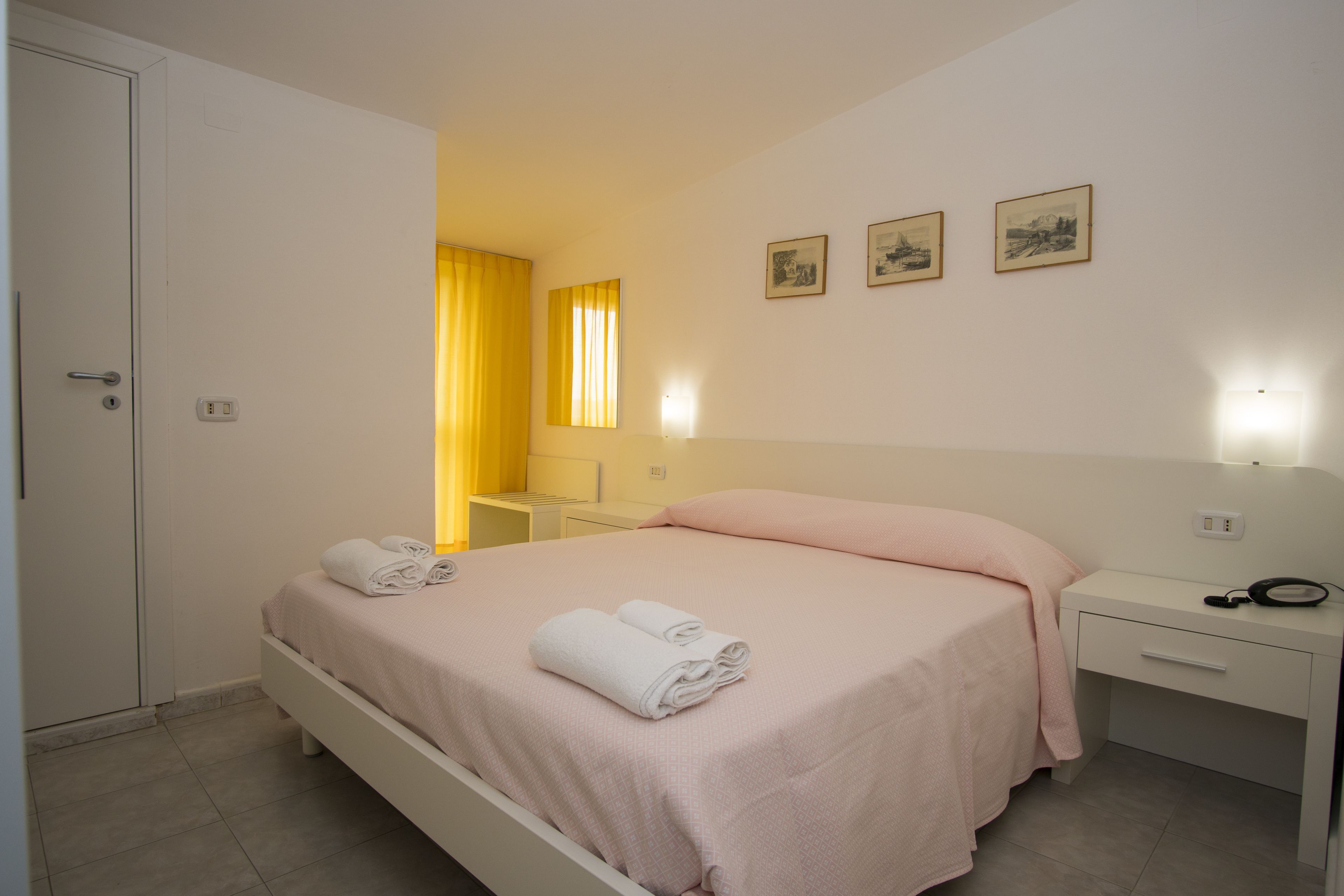 Una habitación de hotel con cama, mesita de noche y armario.