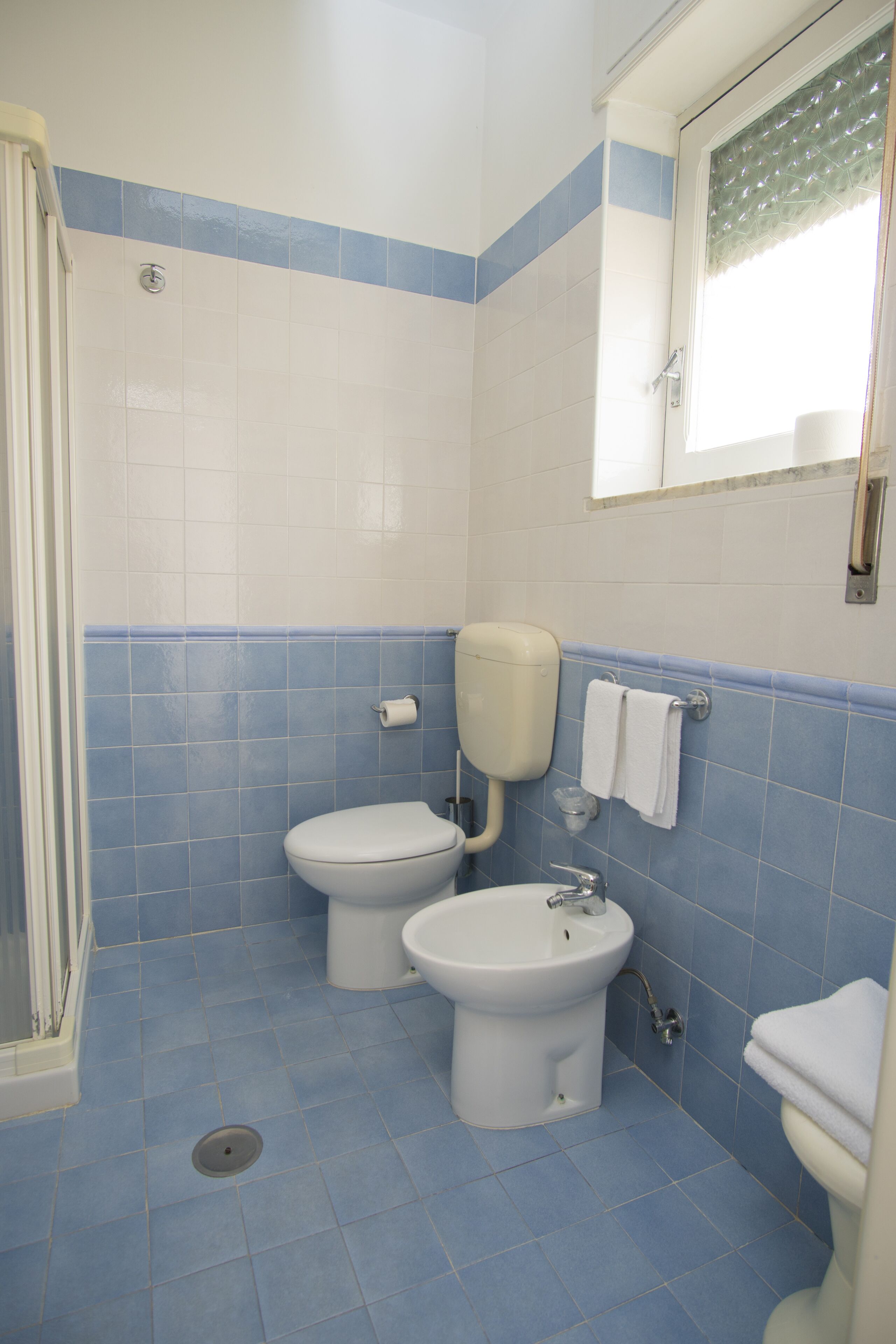 Ein Badezimmer mit zwei Toiletten, einem Waschbecken und einer Dusche.