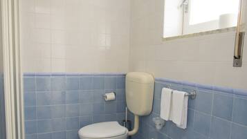 Ein Badezimmer mit zwei Toiletten, einem Waschbecken und einer Dusche.