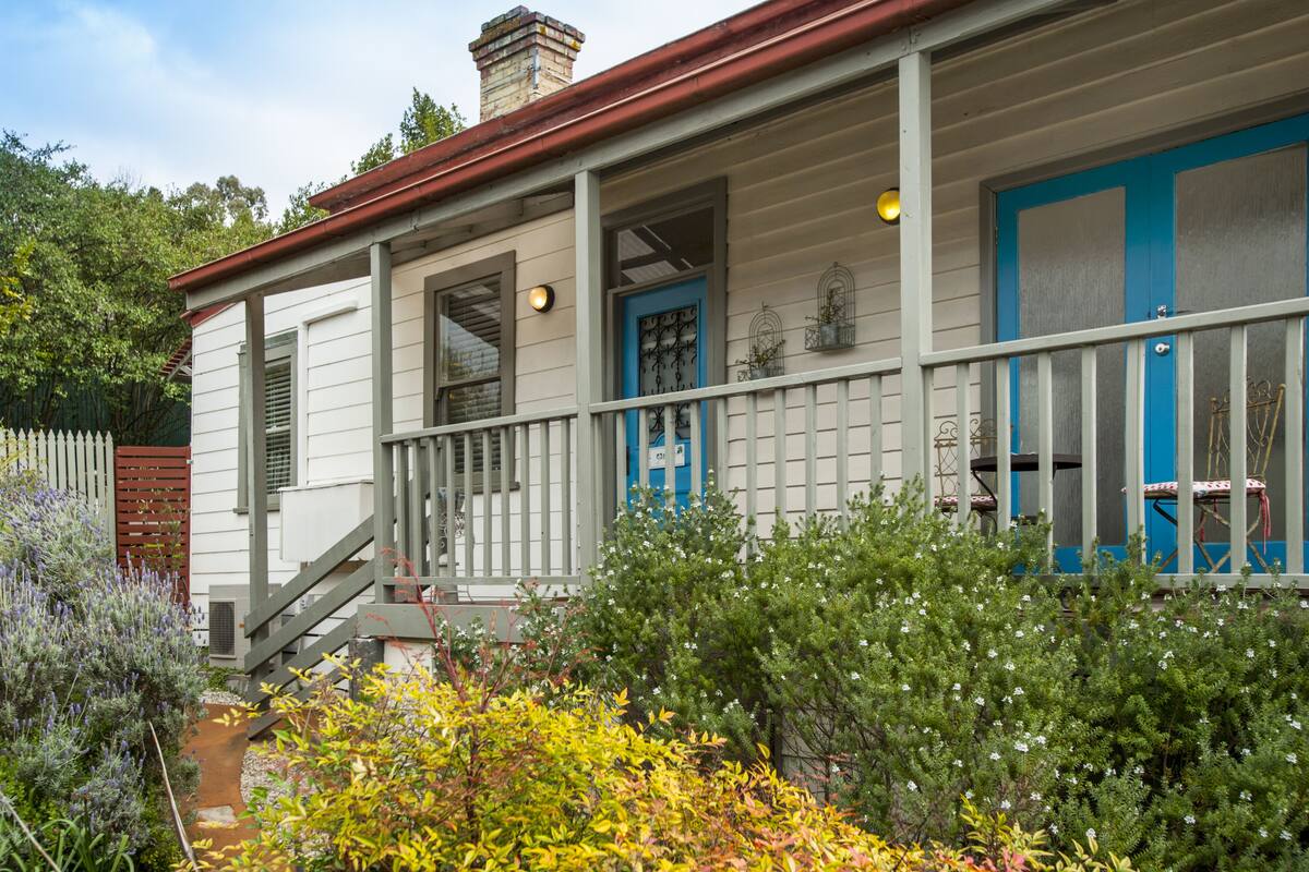 A house with a porch, a blue door, and a staircase leading to the entrance.