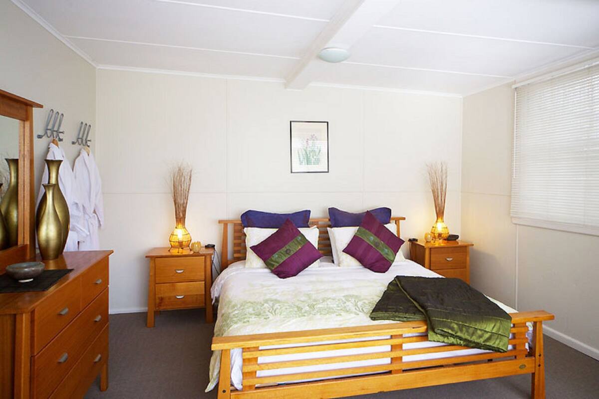 A bedroom with a wooden bed, bedside tables, a dresser, and a mirror.