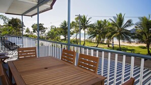 A wooden table and chairs on a balcony with a view of a beach and palm trees. - Apollo Jewel Beachfront Apartments (South Mission Beach)