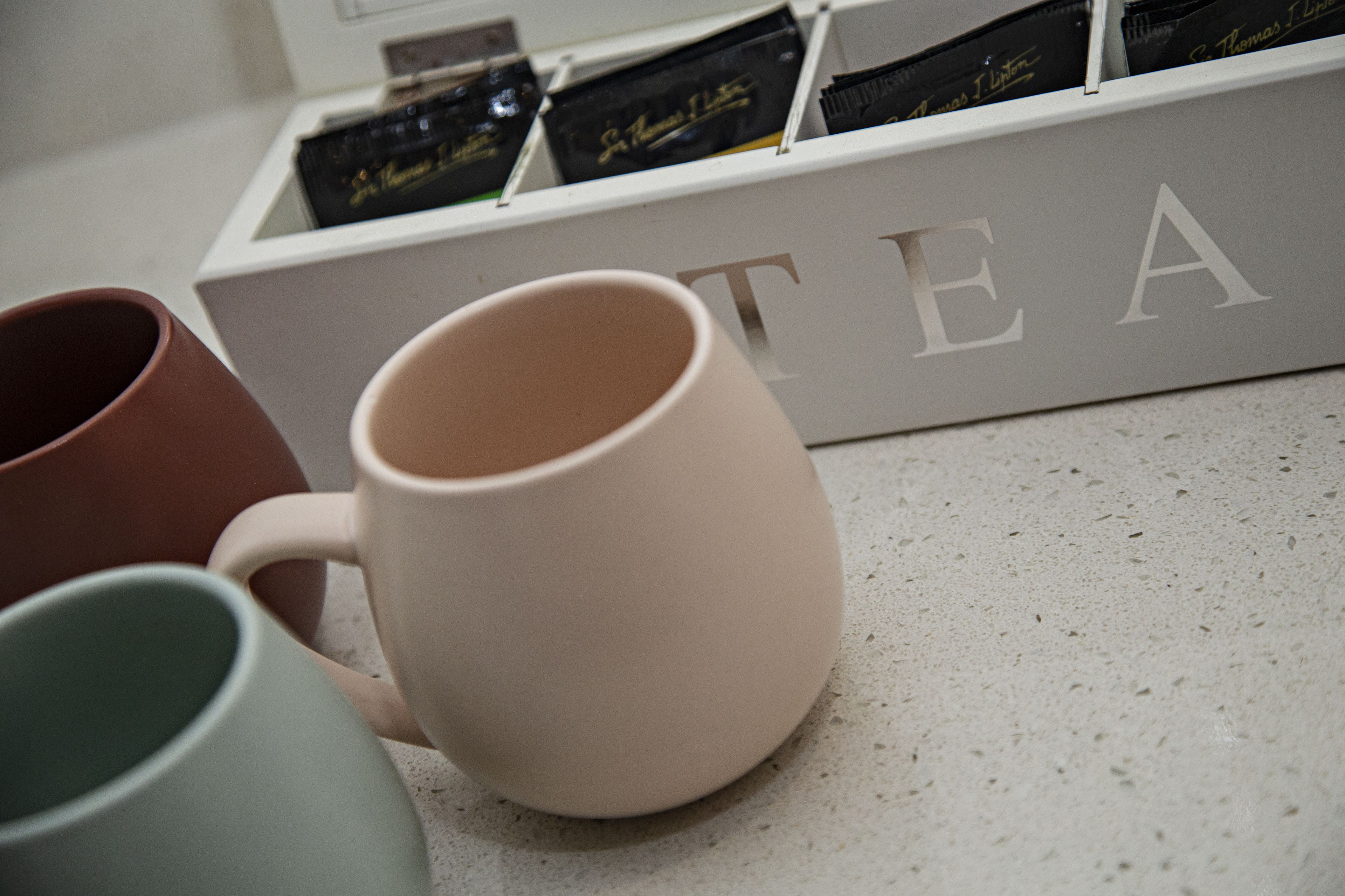 A display of tea boxes and three mugs on a countertop.