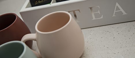 A display of tea boxes and three mugs on a countertop.