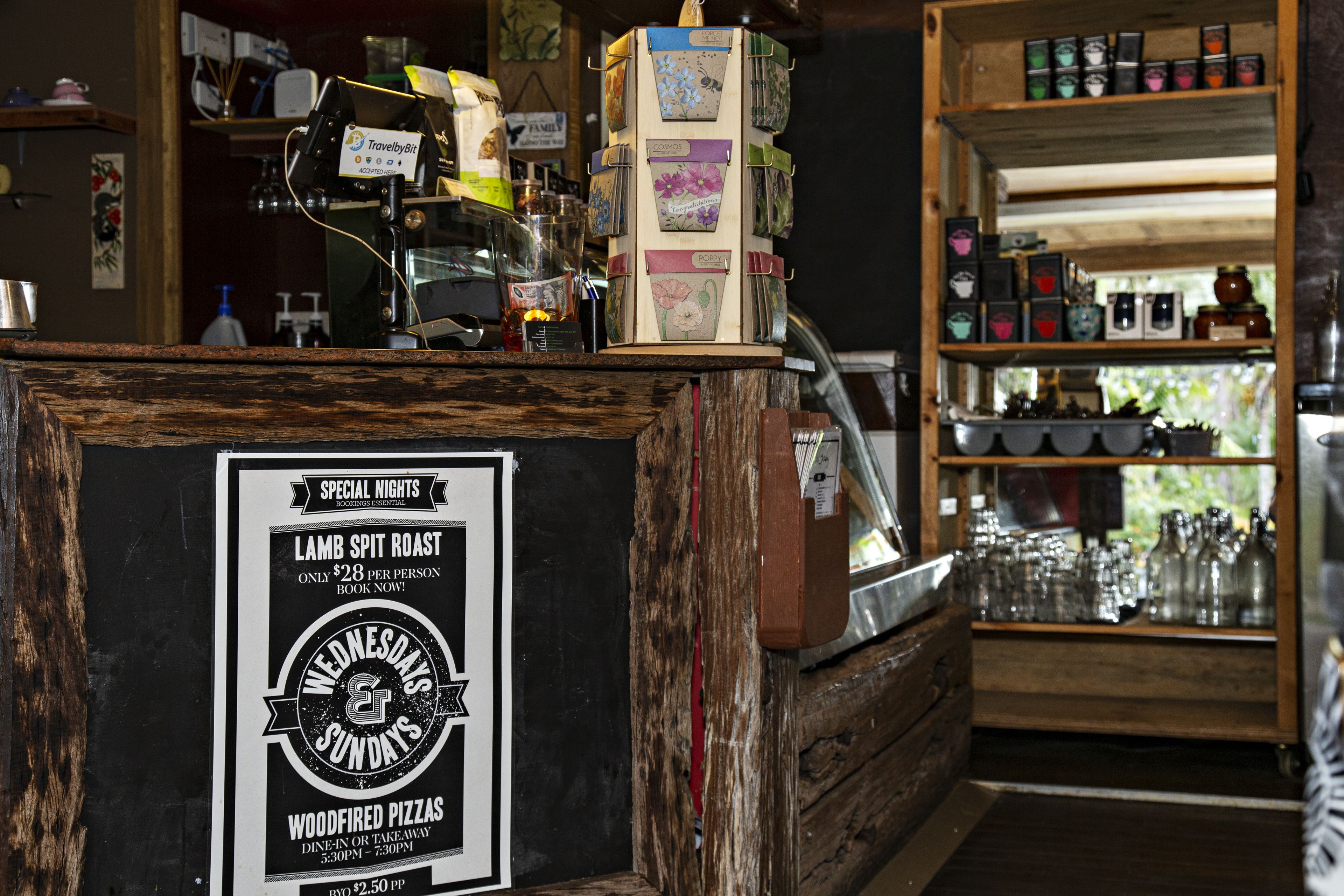 A rustic bar area with a sign advertising lamb spit roast and wood-fired pizzas.