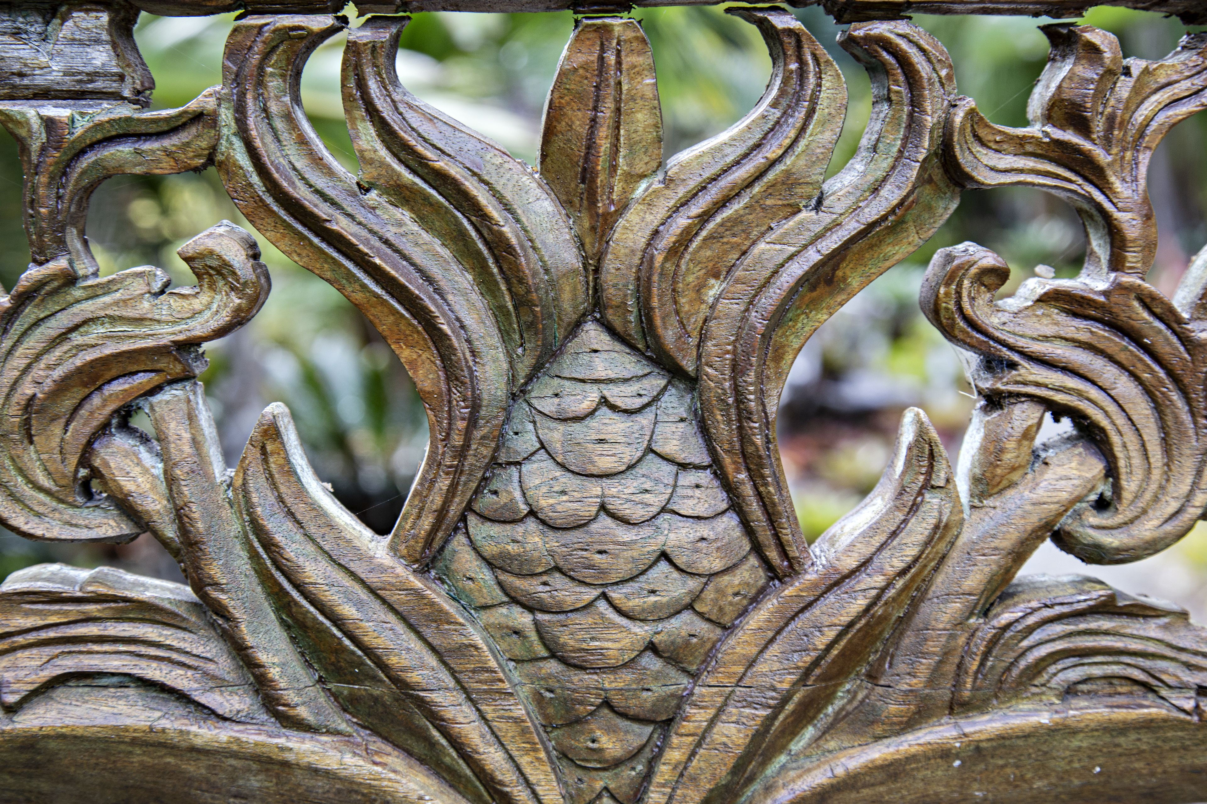 Ett detaljrikt metallstaket med utsmyckade mönster, inklusive ett centralt fiskmotiv och omgivande bladliknande ornament.