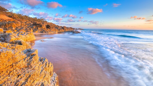 Paisaje costero con acantilados rocosos y una playa.
