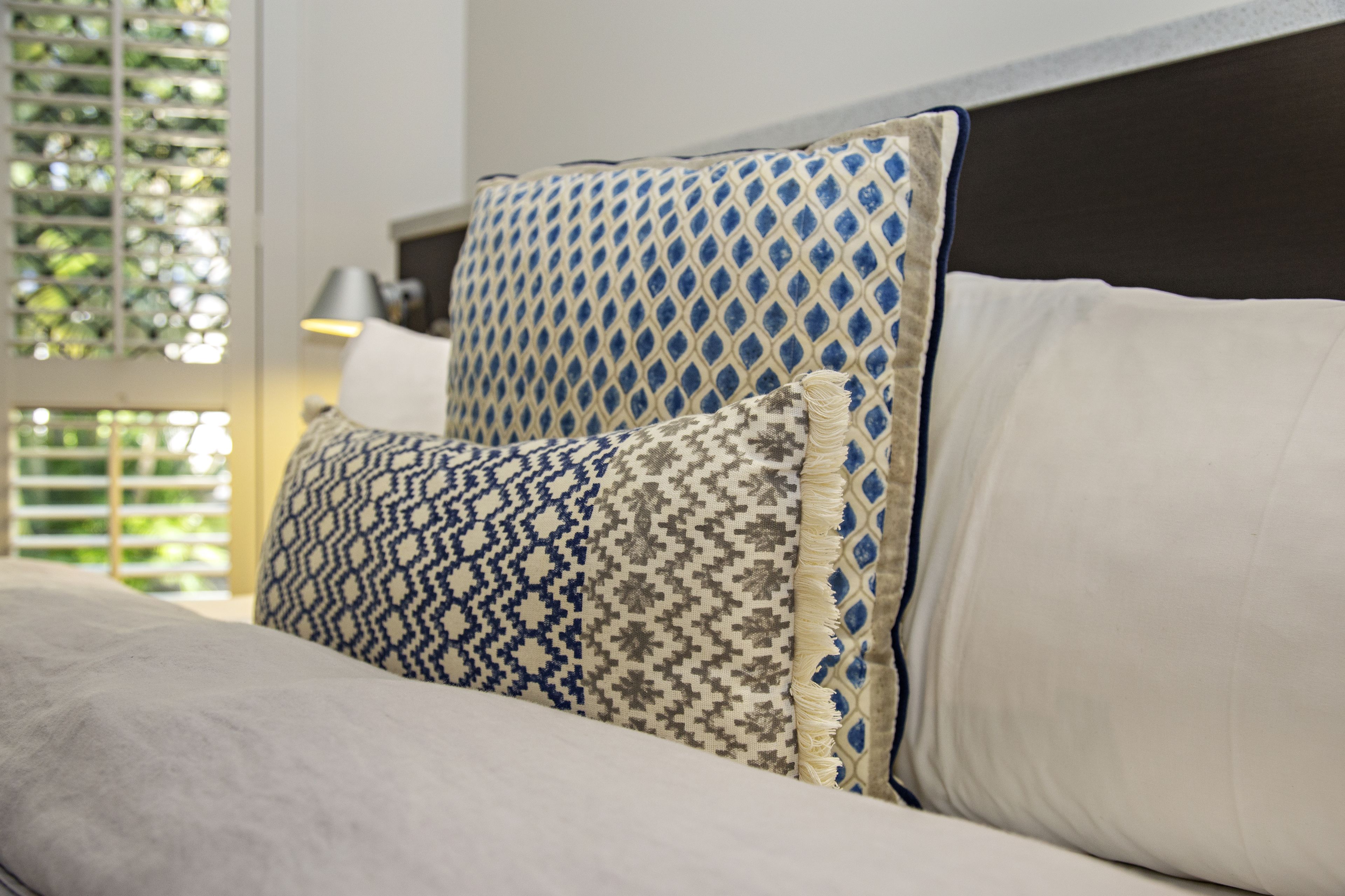 Una cama con almohadas estampadas y un cabecero.