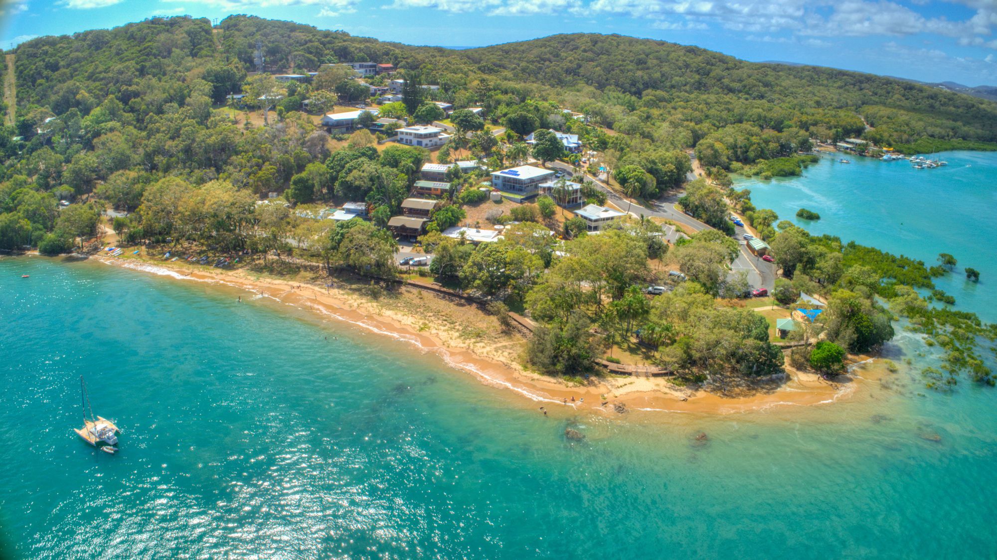 An aerial view of a coastal resort with multiple buildings, a beach, and clear turquoise waters.