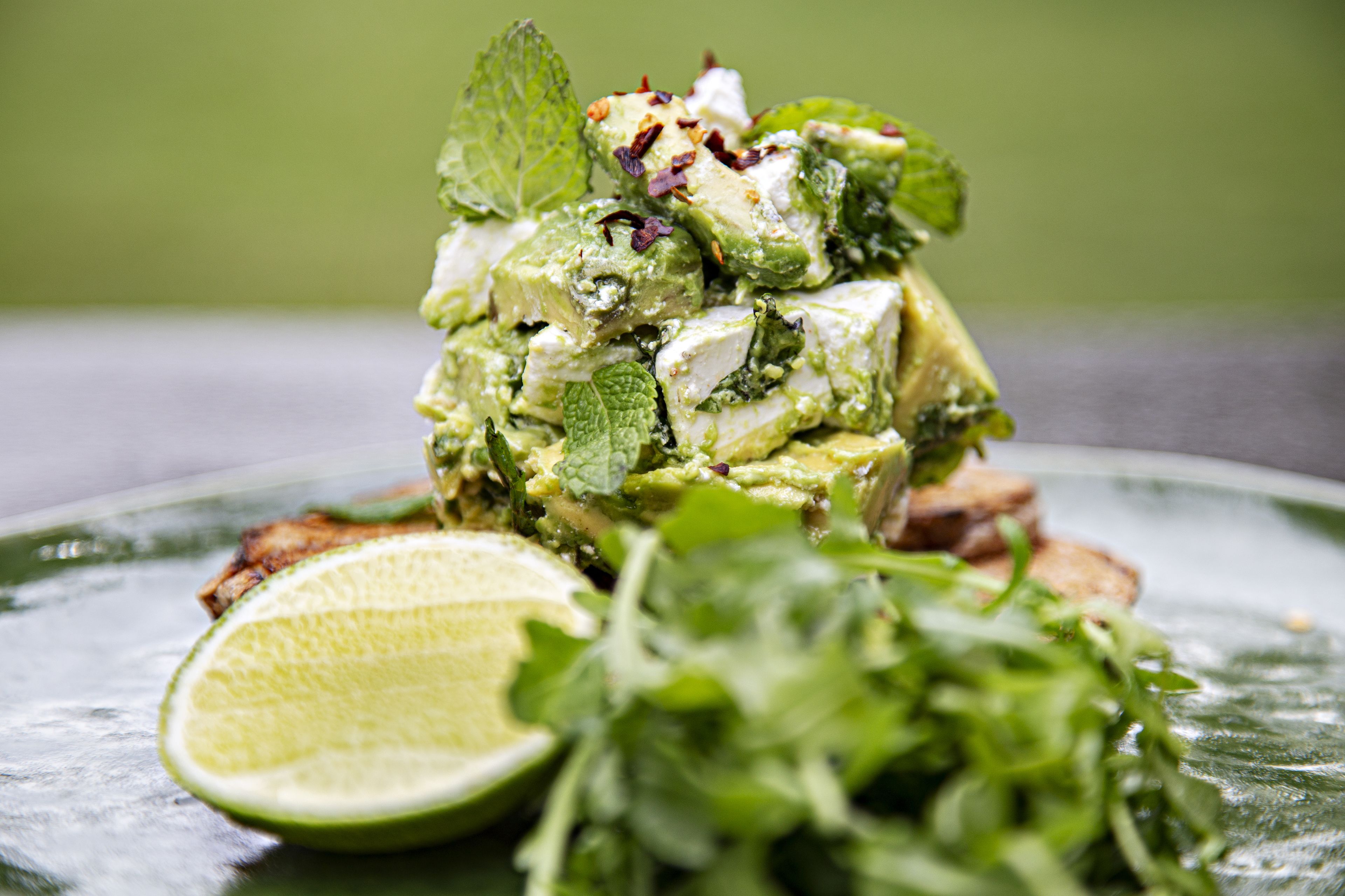 A plate with a food dish, a lime half, and some greens.