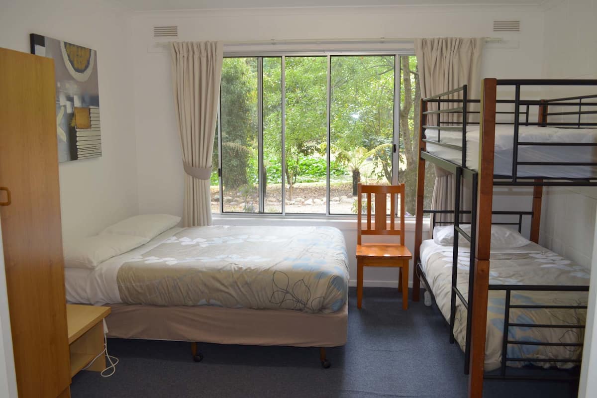 A room with a single bed, a wooden chair, and a bunk bed.
