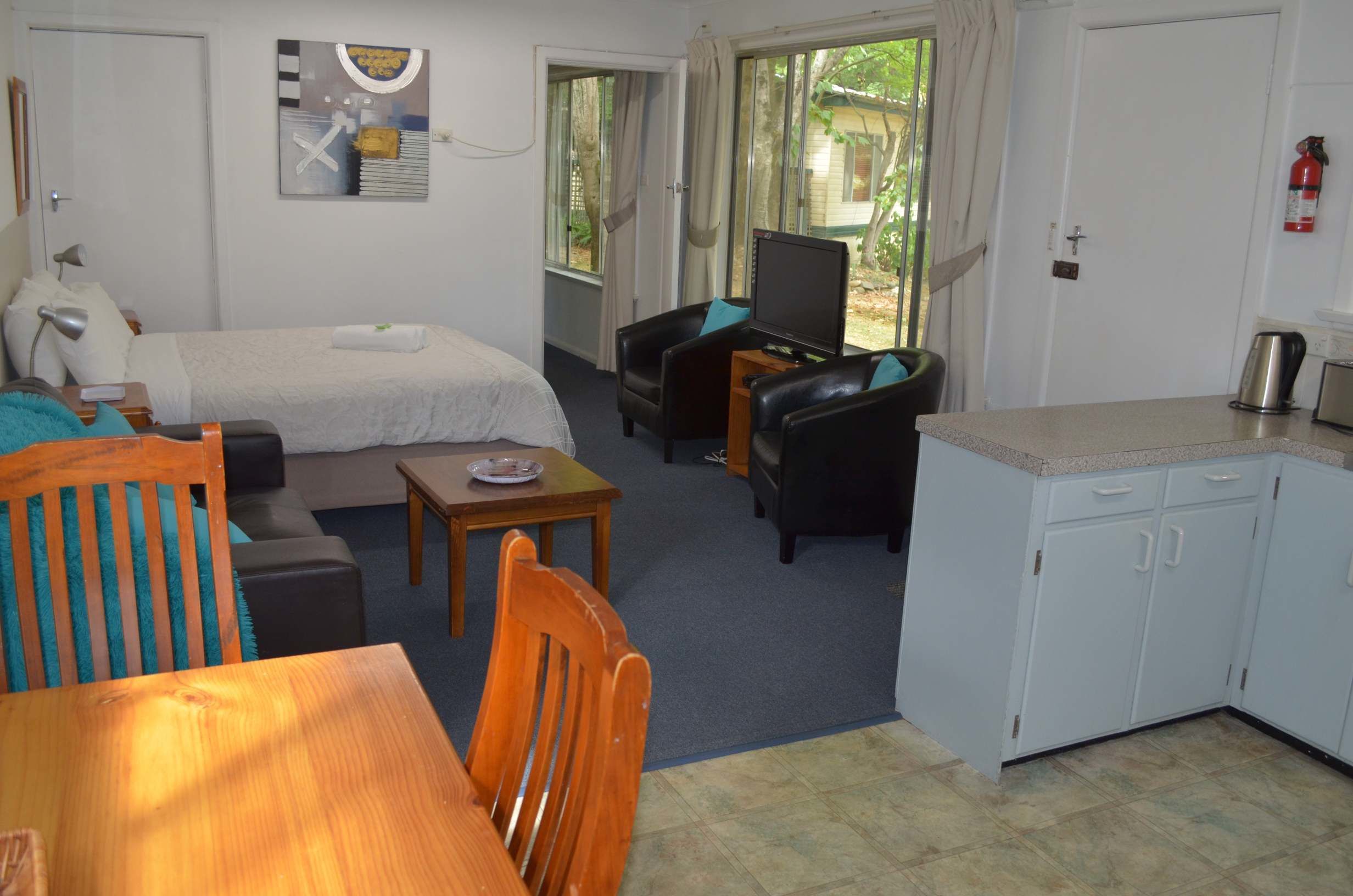 A room with a bed, a desk, a chair, a sofa, and a television.