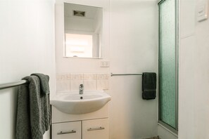 A bathroom with a white sink, a mirror above it, and a towel rack with a towel.
