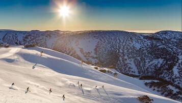Paisaje nevado de montaña con esquiadores y snowboarders.
